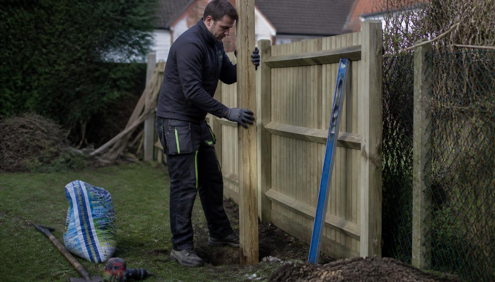 Fencing contractor measuring a garden boundary before installing a new timber fence